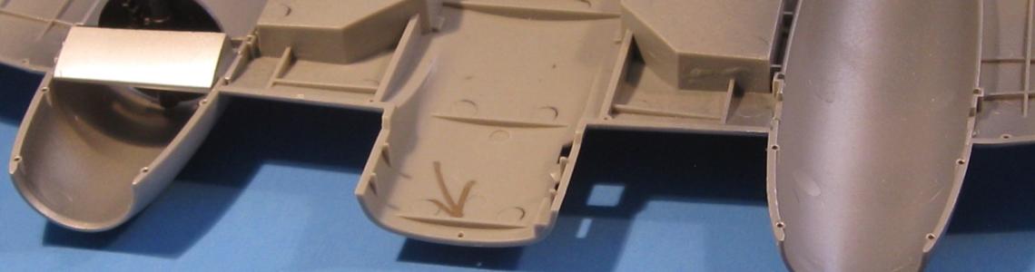 The wide open engine compartment and intake baffles are visible.  The prominent wing spar that crosses the intake is also shown.  Don’t miss drilling out the locating holes for the belly tank.  The holes are shown by gold marker circles.